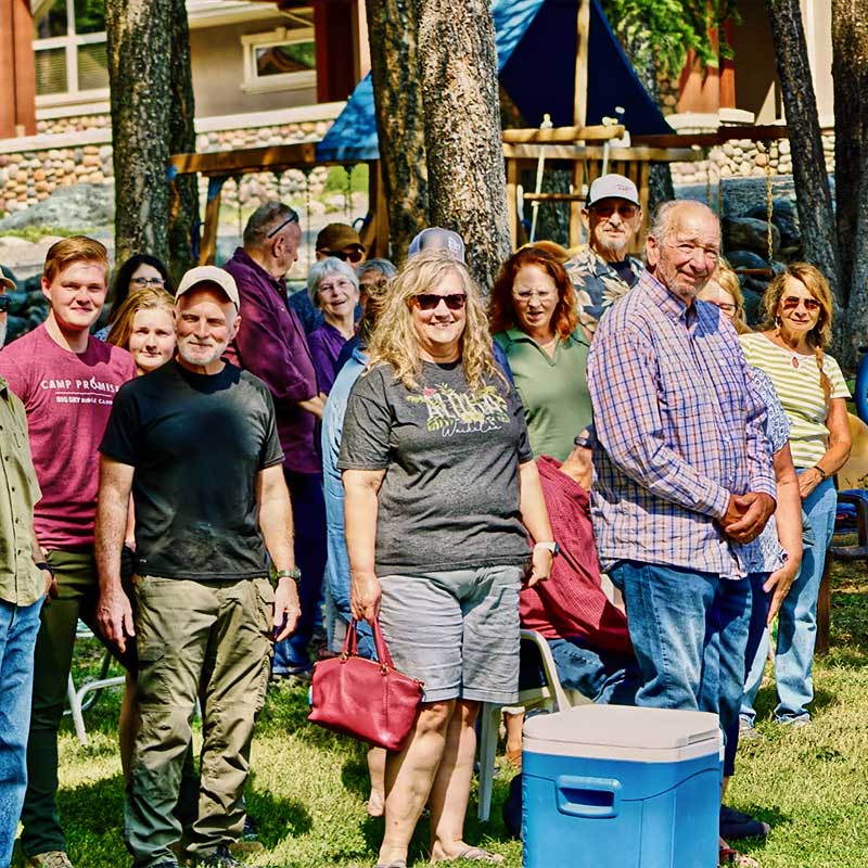 Many members of the <strong>Chapel of Praise</strong> family standing on grass slope smiling for a photo
